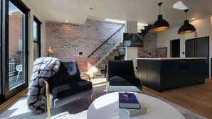 Una sala de estar moderna con chimenea, una escalera y una zona de cocina.