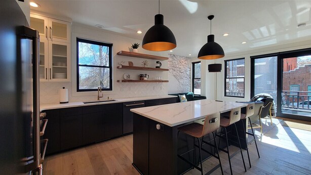 Una cocina moderna con una isla central, iluminación colgante y ventanas amplias.