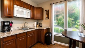A kitchen with wooden cabinets, a microwave, a coffee maker, and a window with blinds. - Jackson Creek: Downtown Jacksonville (Jacksonville)