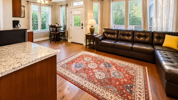A spacious living room with a leather sofa, a coffee table, and a large rug. - Jackson Creek: Downtown Jacksonville (Jacksonville)