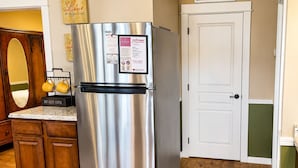 A stainless steel refrigerator with a freezer compartment, a coffee station, wooden cabinets, and a white door. - Jackson Creek: Downtown Jacksonville (Jacksonville)