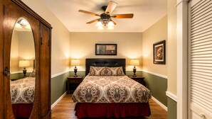A bedroom with a bed, a ceiling fan, two bedside lamps, a large mirror, and a framed picture on the wall. - Jackson Creek: Downtown Jacksonville (Jacksonville)