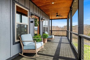 A covered porch with wicker rocking chairs and potted plants. - Cabin w/ Hot Tub · Mtn Views · Pool Table · Pets (Sevierville)
