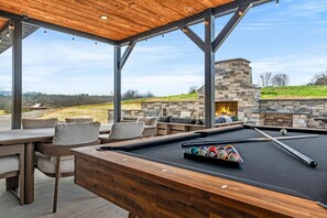 An outdoor pool table with a stone fireplace and seating area. - New 2026-MT Views-1 step entry-5 mi to Dolly-Pets (Sevierville)