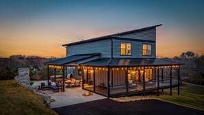 Une maison à deux étages dotée d’un patio couvert, d’un espace salon extérieur et d’un jacuzzi.