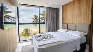 A hotel room with a large window, a bed, a remote control, and a towel on the bed. - Breeze #407 - Double Sea View By Carpediem (João Pessoa)