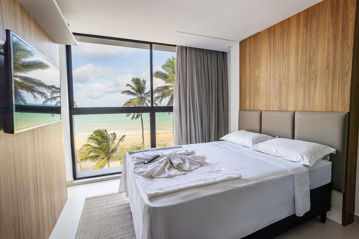 Une chambre d’hôtel avec une grande fenêtre, un lit, une télécommande et une serviette sur le lit.
