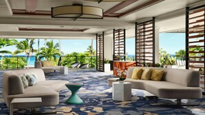 A modern lounge with a patterned carpet, sofas, a coffee table, and a view of the ocean. - Big Island Resort Stay Near Beaches with Spacious 2BR Island View (Waikoloa Village)