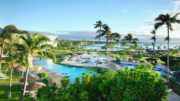 A resort with a large pool, palm trees, and a view of the ocean. - Big Island Resort Stay Near Beaches with Spacious 2BR Island View (Waikoloa Village)