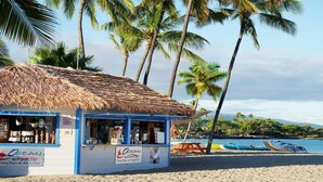 A beachside shop with a thatched roof, a sign for Ocean Sports, and a view of the beach and water. - Big Island Resort Stay Near Beaches with Spacious 2BR Island View (Waikoloa Village)