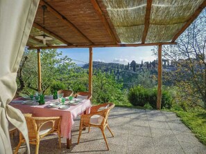 Ein Essbereich im Freien mit Korbstühlen und einem Tisch für zwei Personen mit Blick auf eine schöne Landschaft.