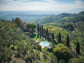 Eine Villa mit Swimmingpool, umgeben von Weinbergen und Zypressen.