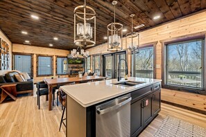 A modern kitchen with a central island, wooden ceiling, and large windows. - LUXE-Mtn Views-1 mi to PKWY-Pool-Rooftop Bar-Pets (Pigeon Forge)