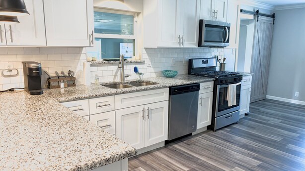 A modern kitchen with white cabinets, granite countertops, a built-in microwave, and a dishwasher. - The Grape Stay of Texas- in the heart of Grapevine Main Street (Grapevine)