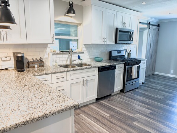 A modern kitchen with white cabinets, granite countertops, a built-in microwave, and a dishwasher. - The Grape Stay of Texas- in the heart of Grapevine Main Street (Grapevine)