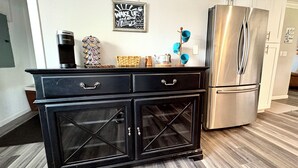 A kitchen with a black cabinet, a stainless steel refrigerator, and a wall-mounted sign. - The Grape Stay of Texas- in the heart of Grapevine Main Street (Grapevine)