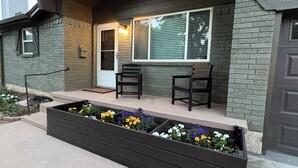 A house with a porch, two chairs, a flower bed, and a window with blinds. - The Grape Stay of Texas- in the heart of Grapevine Main Street (Grapevine)