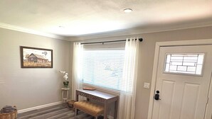 A room with a wooden floor, a bench, a desk, a door with a window, and a framed picture on the wall. - The Grape Stay of Texas- in the heart of Grapevine Main Street (Grapevine)