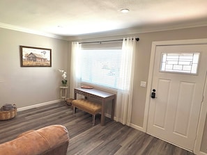 A room with a wooden floor, a bench, a desk, a door with a window, and a framed picture on the wall. - The Grape Stay of Texas- in the heart of Grapevine Main Street (Grapevine)