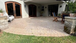 Eine Terrasse mit Pflasterboden, einer Holztür und einer Sitzgruppe mit Tisch und Stühlen.