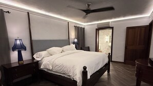 Ein Schlafzimmer mit Bett, Nachttischen, Deckenventilator und einer Tür zum Badezimmer.