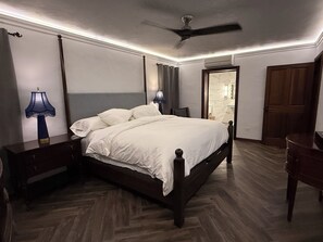 A bedroom with a bed, bedside tables, a ceiling fan, and a door leading to a bathroom. - Luxury 2 Bedroom, 2 Bath Executive Retreat (Hamilton)
