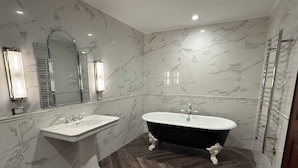 Ein Badezimmer mit einem Standwaschbecken, einer freistehenden Badewanne und einem Spiegel über dem Waschbecken.