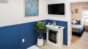 Un salon avec une cheminée, un téléviseur à écran plat, un tableau et une plante en pot.