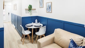 Un coin repas avec une table ronde, des chaises blanches et un canapé beige.