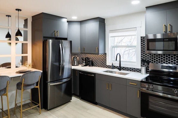 A modern kitchen with a refrigerator, stove, and microwave.