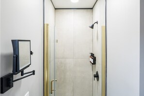 Une salle de bain moderne avec une douche à parois de verre, un miroir fixé au mur et un porte-serviettes.