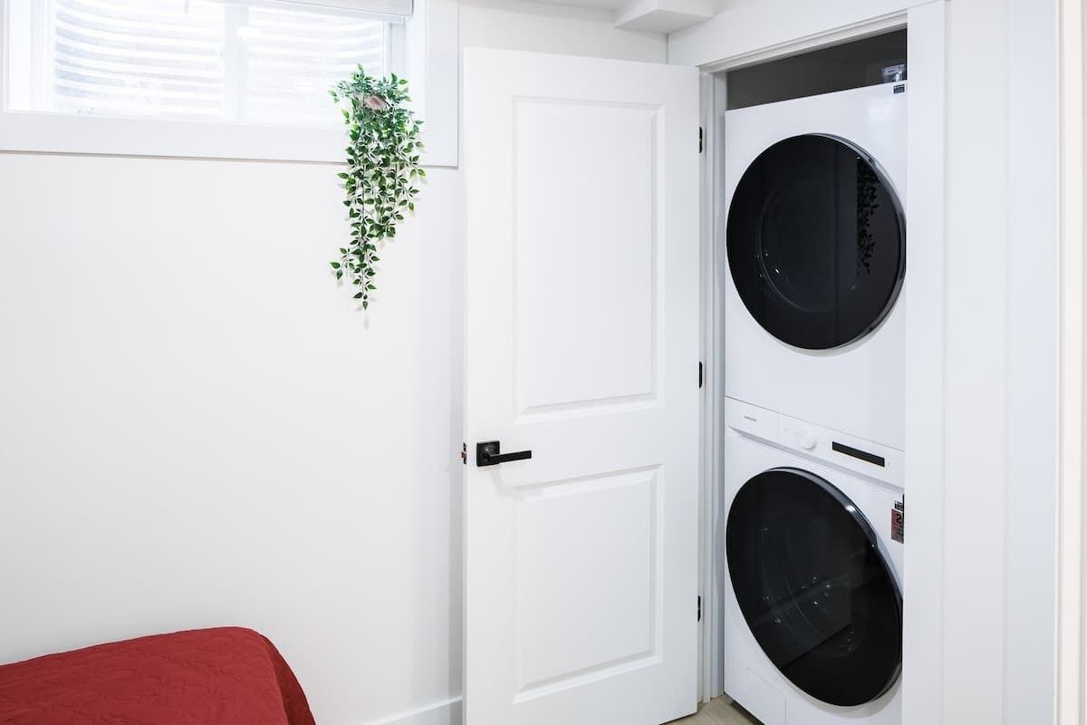Ein Zimmer mit einer weißen Tür, einem roten Bett und einer an der Wand befestigten Pflanze.