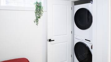 Ein Zimmer mit einer weißen Tür, einem roten Bett und einer an der Wand befestigten Pflanze.