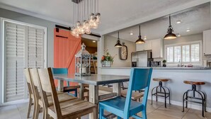 Una cucina moderna con isola centrale, illuminazione a sospensione e zona pranzo con sedie in legno.