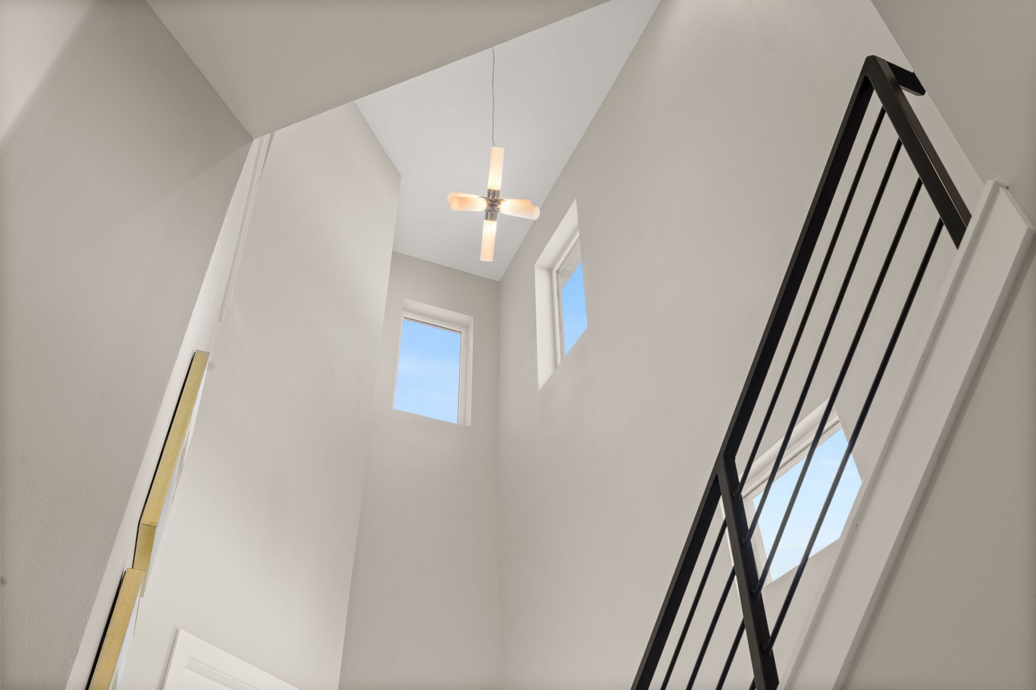 A staircase with a black railing, a ceiling fan, and a small window.