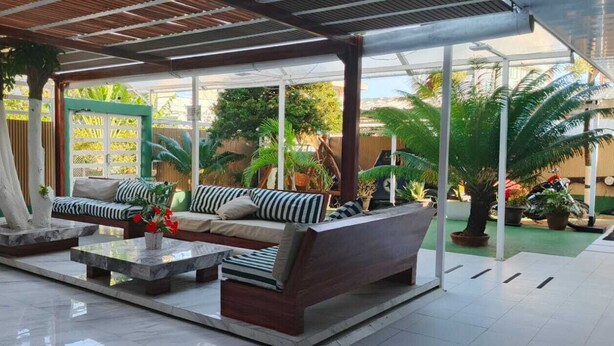 A modern outdoor seating area with a sofa, a coffee table, and potted plants.