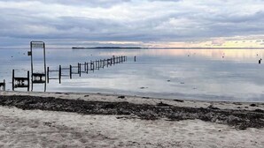 Een strand met een houten omheining en een bord.