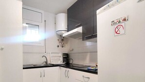 Een keuken met witte kastjes, een zwart aanrecht en een witte koelkast.