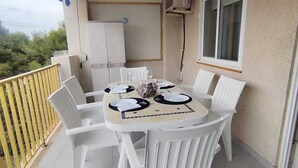 Een balkon met een ronde tafel gedekt voor vier personen, witte stoelen en een gele balustrade.