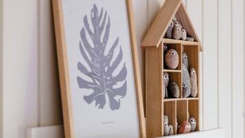 A framed leaf artwork and a wooden house-shaped shelf with rocks.