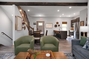 Ein modernes Interieur mit Treppe, grünen Sesseln, einem Essbereich und einer Küche.