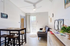 A modern kitchen with a dining table, bar stools, and a ceiling fan. - Liyann - Proche plage - Terre Sainte (Saint-Pierre)