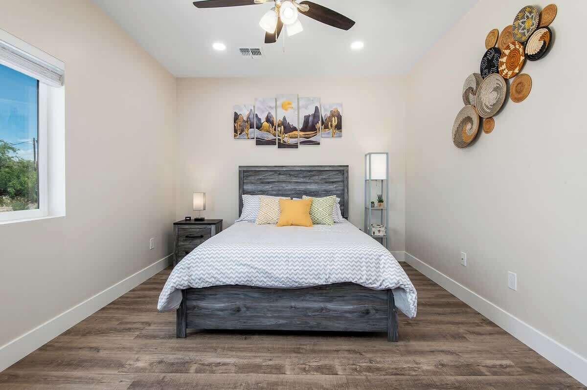 Un dormitorio con cama, ventilador de techo, ventana y una pared decorada con placas.