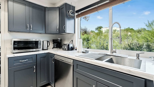 Una cucina moderna con mobili scuri, un forno a microonde, una macchina da caffè e un lavello.