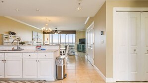 A spacious kitchen with a central island, a dining area with a view, and a hallway leading to a door. - New Listing! Lost Key San Andres| Two pools| Private Beach Club| Tennis| Free Golf Round Daily! (Pensacola)
