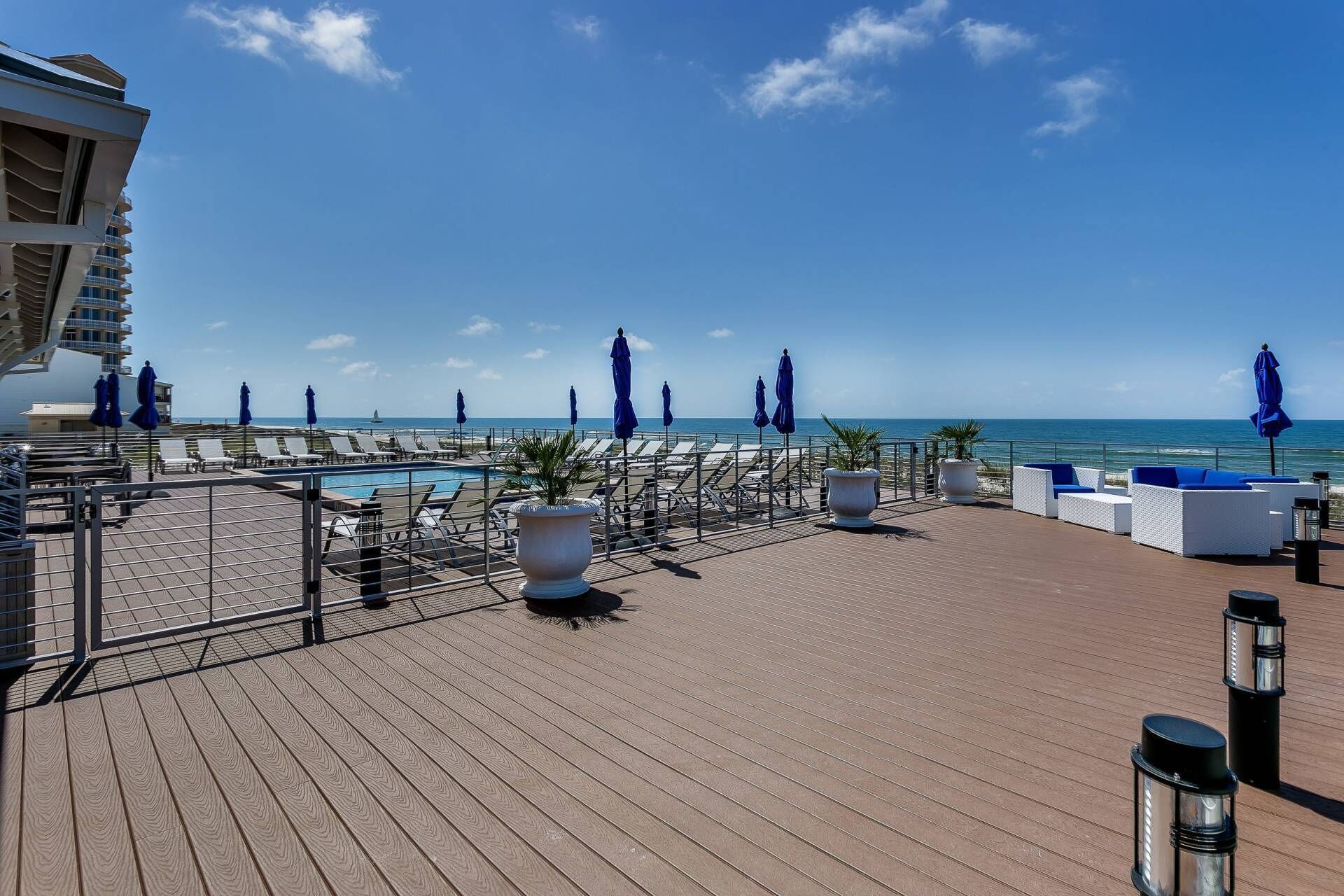 A rooftop deck with lounge chairs, umbrellas, and a pool.