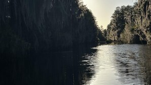A calm river with trees on both sides, reflecting the sky.