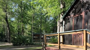 A picnic table in a park with a wooden deck and a cabin in the background.