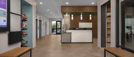 A hotel lobby with a reception desk, seating area, and a wall with a QR code.