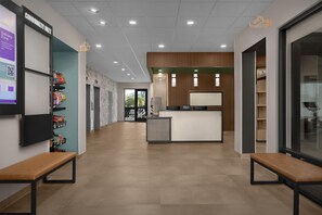 A hotel lobby with a reception desk, seating area, and a wall with a QR code. - Livsmart Studios By Hilton Huntsville Research Park Area (Huntsville)